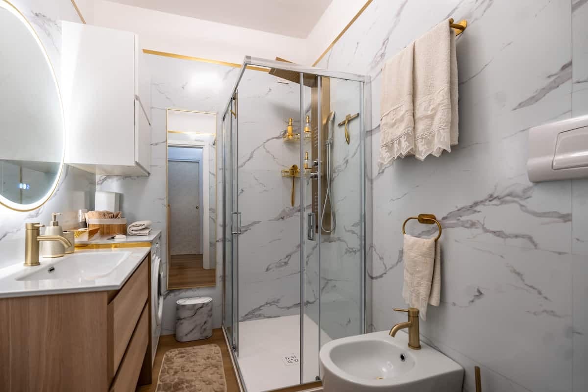 Bagno in marmo con doccia e rubinetteria dorata