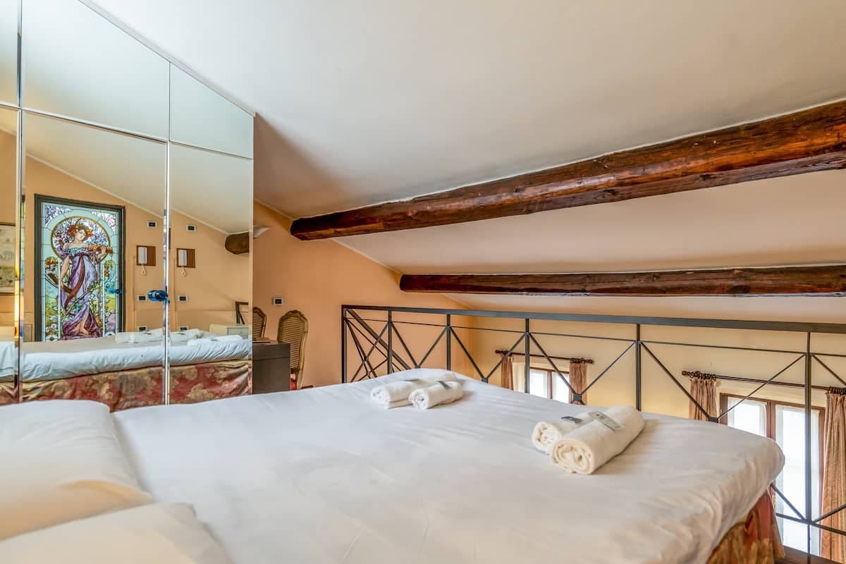 Letto matrimoniale sul soppalco, sotto le travi in legno a vista