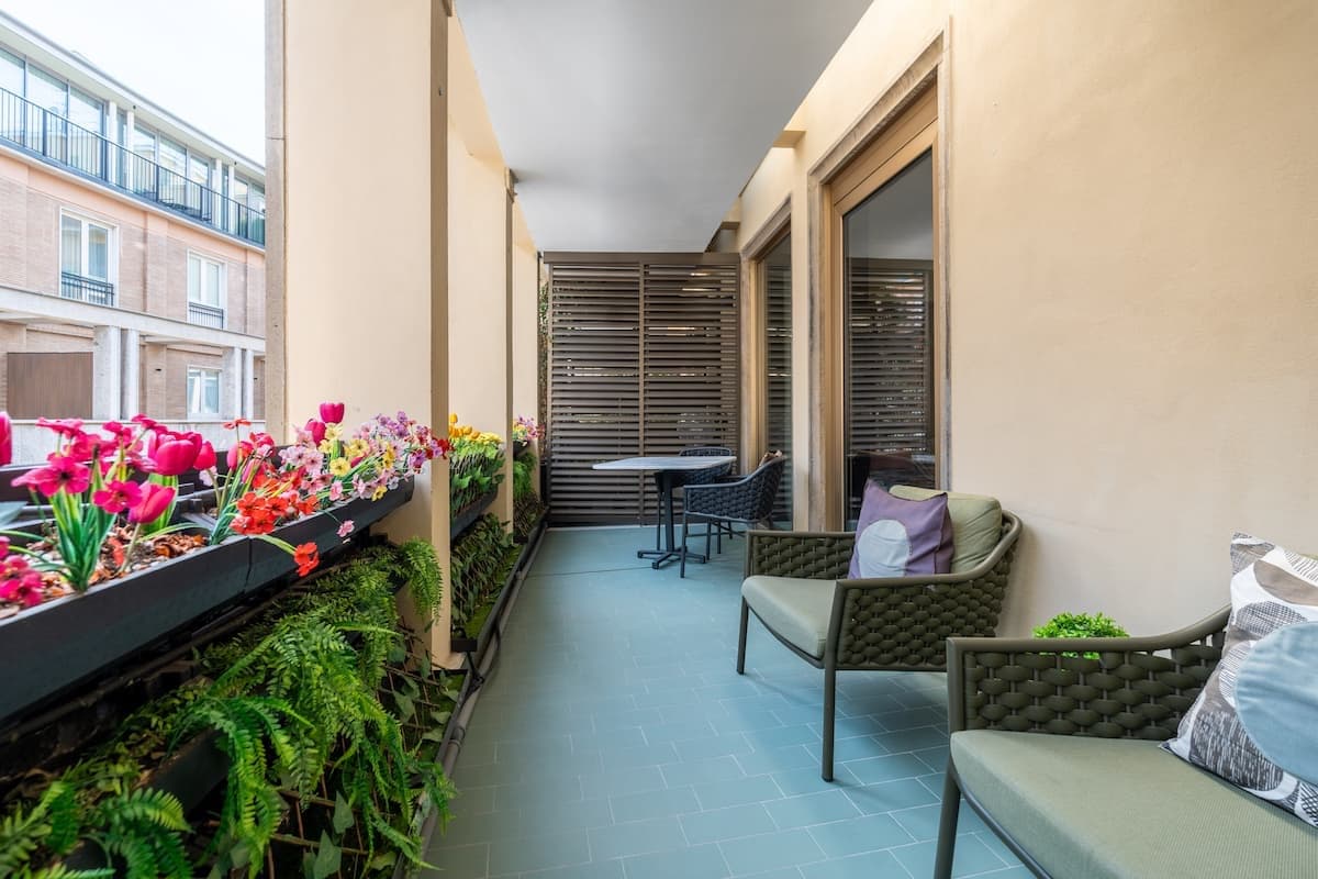 Terrazzo lungo la facciata con sedute in corda e fiori