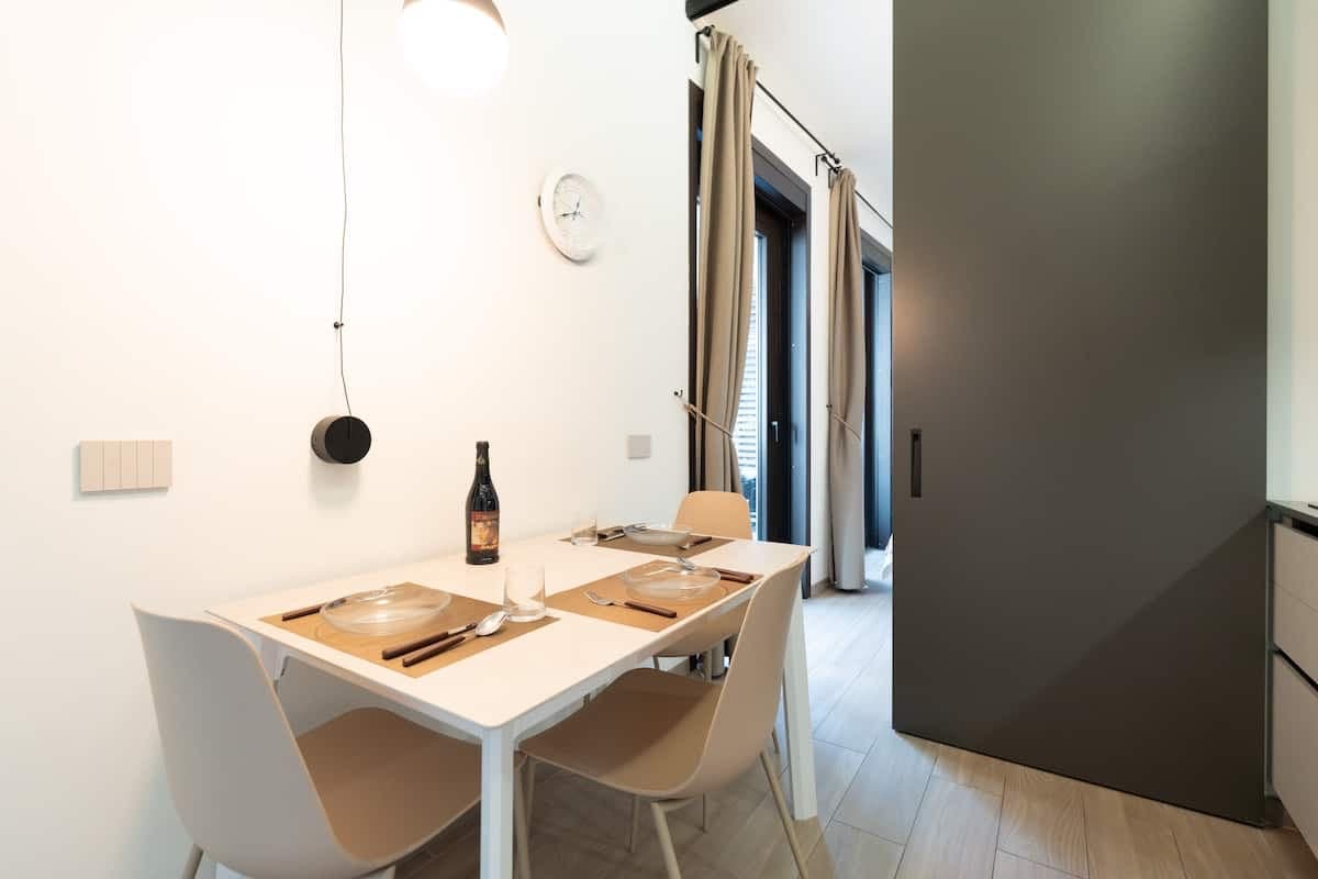 Zona pranzo con tavolo bianco e lampada a sospensione