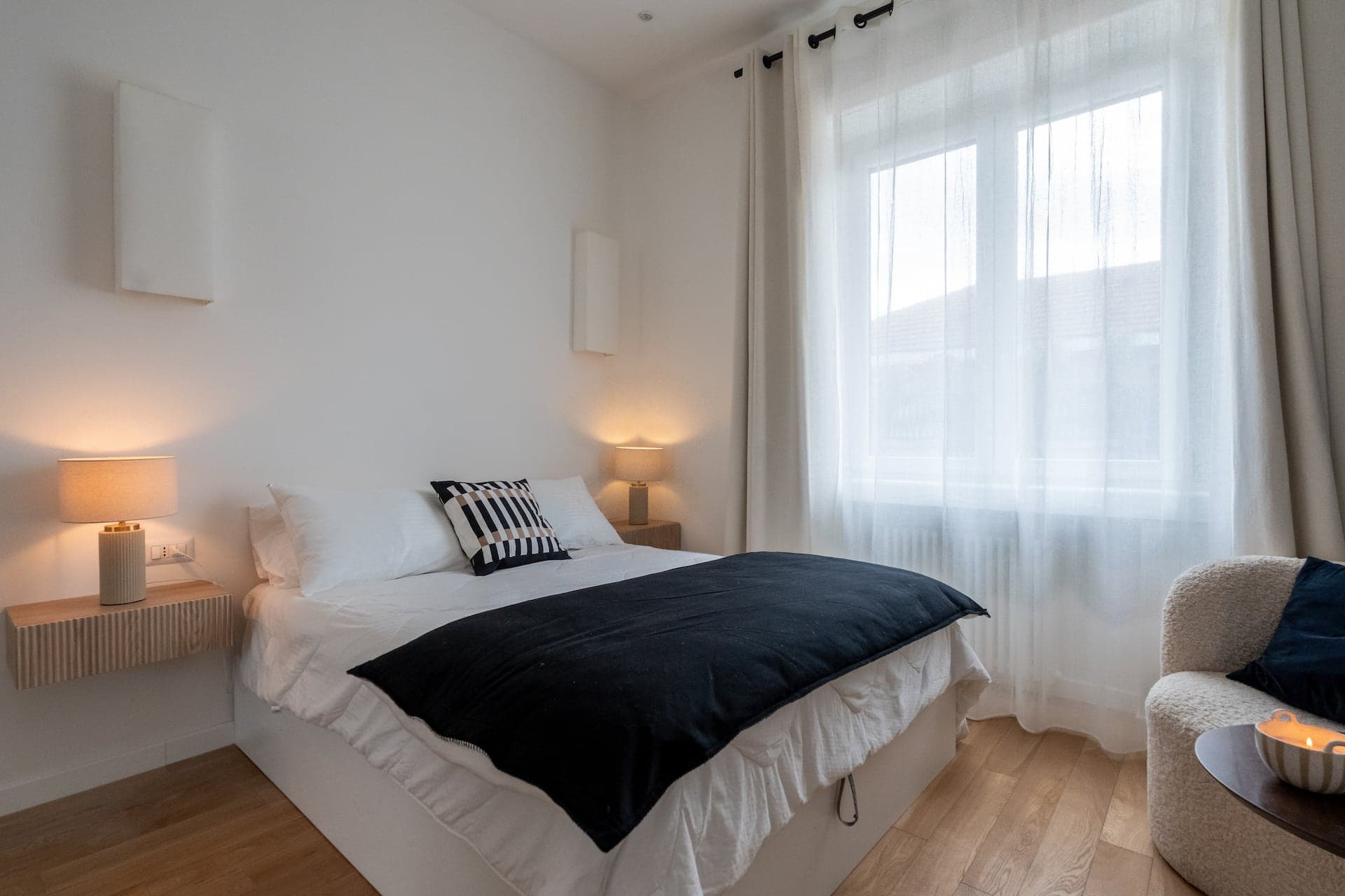 Camera da letto con coperta scura e tende chiare