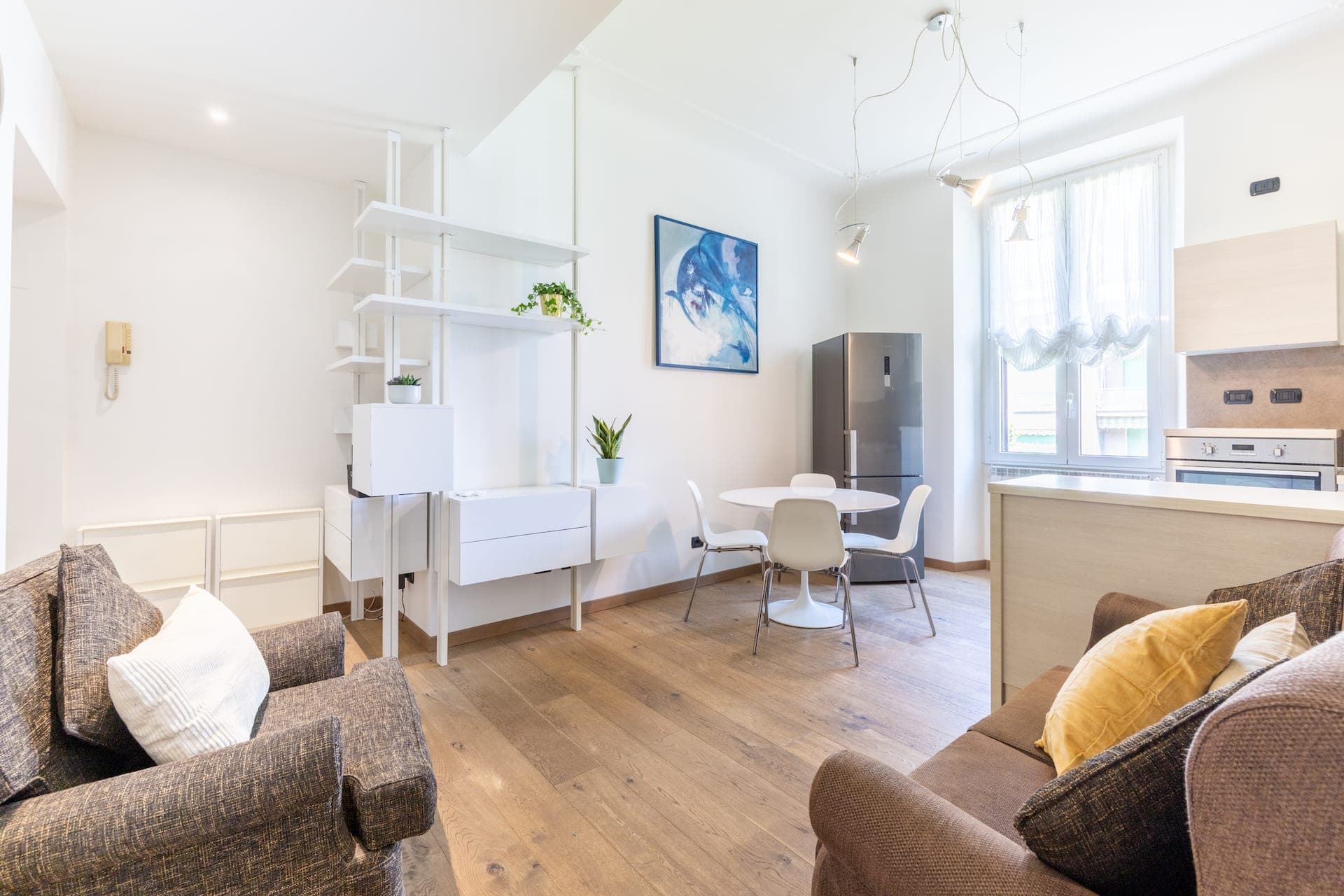 Soggiorno open space con cucina e libreria bianca